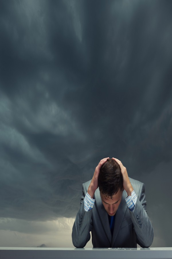 Depressed_young_businessman_sitting_wet_under_rain.jpeg